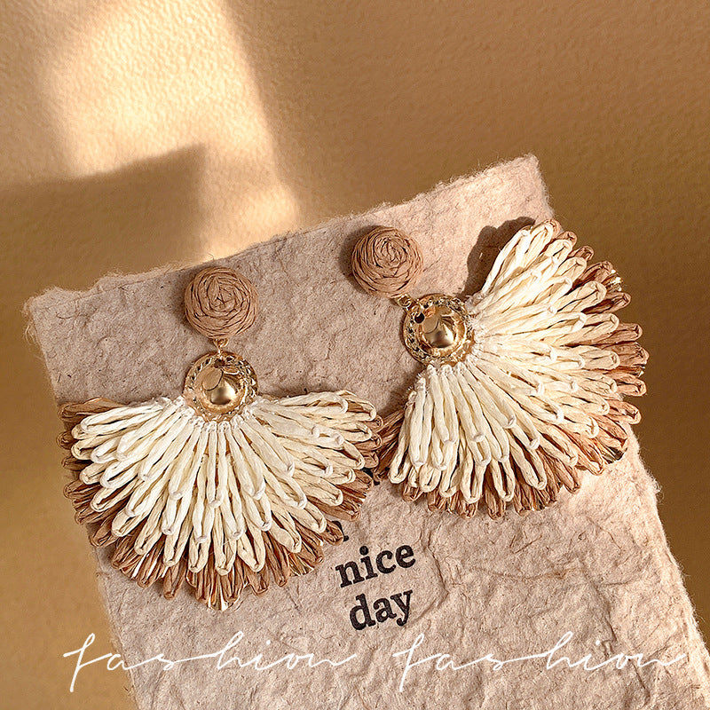 Ethnic handwoven raffia grass earrings with colorful floral accents - high-end bohemian style for travel photography and vacation looks