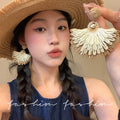 Ethnic handwoven raffia grass earrings with colorful floral accents - high-end bohemian style for travel photography and vacation looks