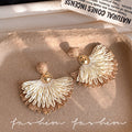 Ethnic handwoven raffia grass earrings with colorful floral accents - high-end bohemian style for travel photography and vacation looks