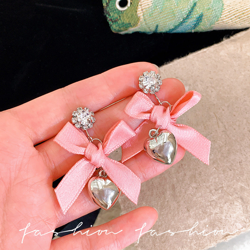 "instagram-worthy, 'rich girl' style pink bow and heart pendant earrings – unique, sweet, and perfect for vacation. wholesale available."