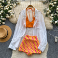 Vacation-ready bikini set for the hot girl summer look: orange cami top, floral print skirt, and sun-protective cardigan – a chic and stylish three-piece outfit