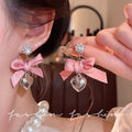 "instagram-worthy, 'rich girl' style pink bow and heart pendant earrings – unique, sweet, and perfect for vacation. wholesale available."
