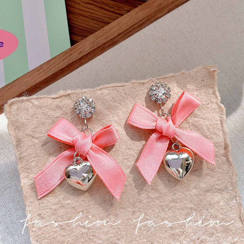 "instagram-worthy, 'rich girl' style pink bow and heart pendant earrings – unique, sweet, and perfect for vacation. wholesale available."