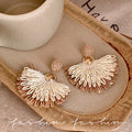 Ethnic handwoven raffia grass earrings with colorful floral accents - high-end bohemian style for travel photography and vacation looks
