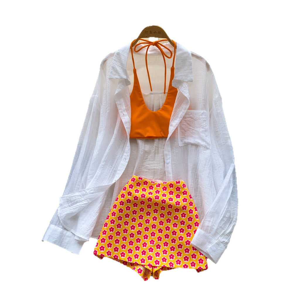 Vacation-ready bikini set for the hot girl summer look: orange cami top, floral print skirt, and sun-protective cardigan – a chic and stylish three-piece outfit