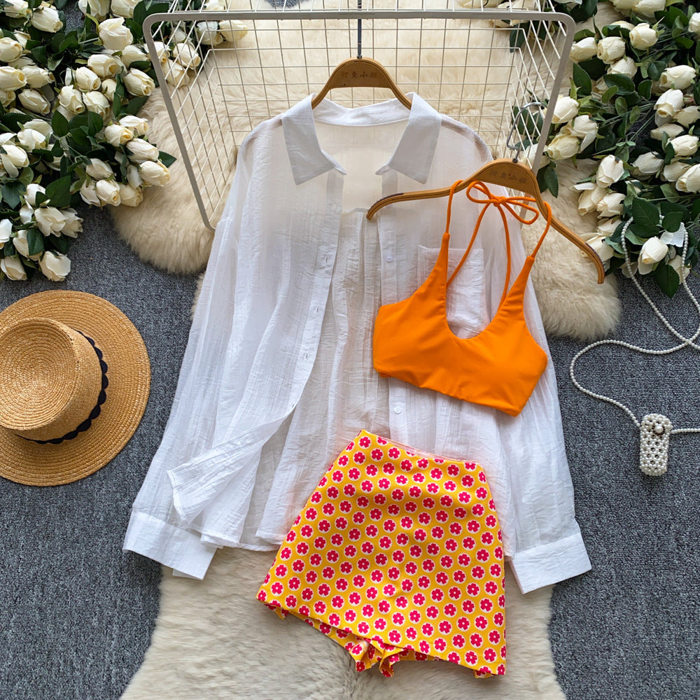 Vacation-ready bikini set for the hot girl summer look: orange cami top, floral print skirt, and sun-protective cardigan – a chic and stylish three-piece outfit