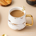 Nordic-inspired ceramic coffee mug, teacup, and saucer set with gold-traced marble pattern and wooden lid